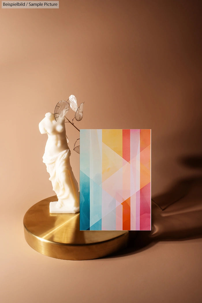 Statue of Venus on round pedestal with colorful geometric painting in foreground against a beige backdrop.