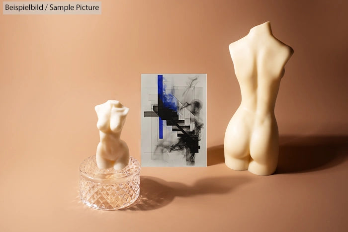 Sculptures of torso and crystal bowl with abstract painting on beige background.