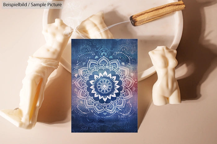 White candles shaped like torsos on plate with blue mandala card and churro. Sample image text overlay.