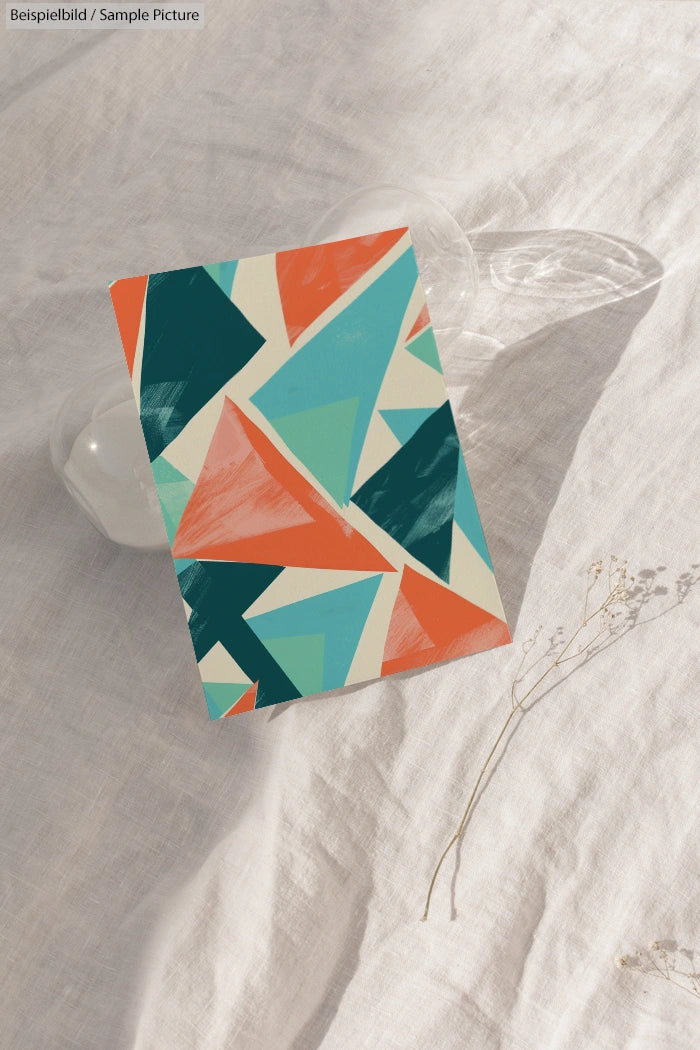 Colorful abstract geometric design with triangles in teal, orange, and cream on a textured background.