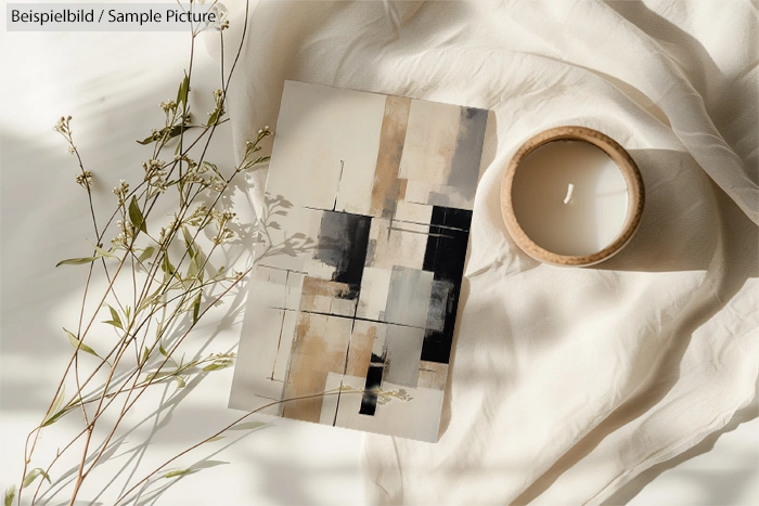 Geometric abstract painting with neutral tones beside a lit candle and dried flowers on a soft fabric backdrop.