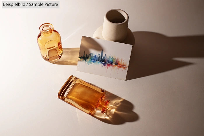 Two amber glass bottles and a vase with a cityscape postcard on a white surface casting shadows.