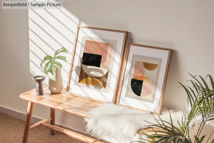 Two framed abstract art pieces on a wooden bench, with potted plants and sunlight casting shadows on the wall.