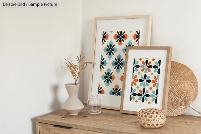 Two framed abstract floral prints on a wooden dresser with vases and woven decor accents.