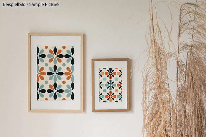 Two framed abstract floral prints on a wall beside dried plant decor.