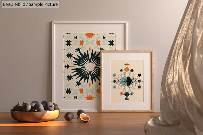 Framed abstract art with star patterns next to a bowl of figs on a wooden surface.