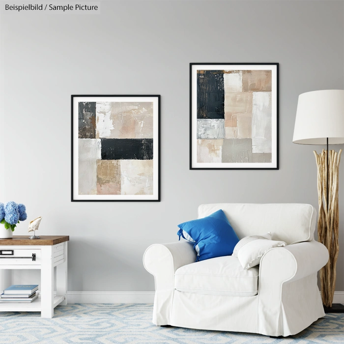 Living room with abstract art on wall, white armchair with blue cushion, and a wooden side table with decorative items.