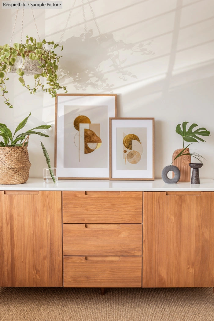 Mid-century modern console with framed abstract art, hanging plant, and decorative objects in a bright room.