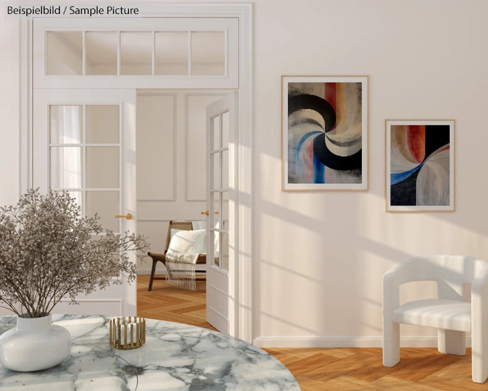 Modern room with abstract paintings, marble table, and white chair, featuring natural light and wooden flooring.