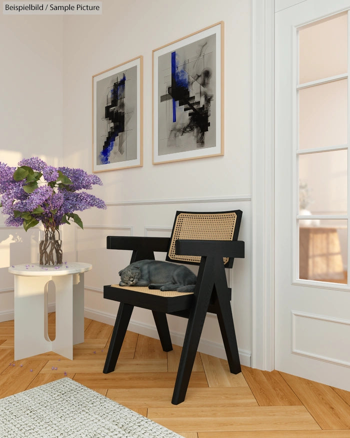 Modern room with black chair, cat sleeping, abstract art on walls, and vase of purple flowers on white table.