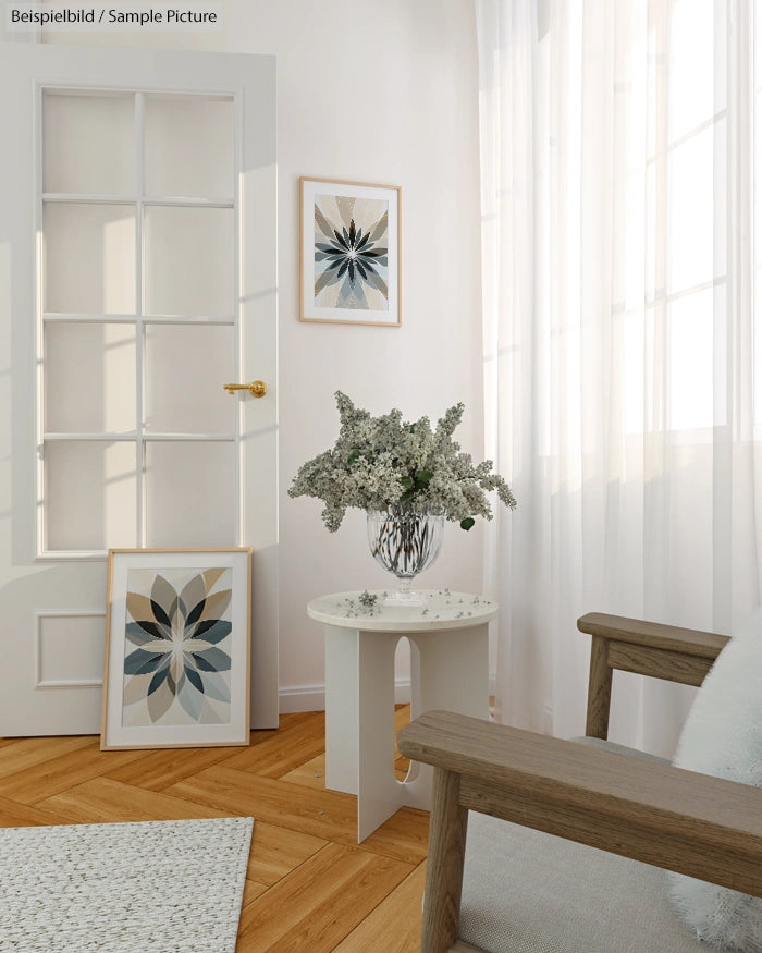 Bright living room with modern decor, featuring a vase of flowers on a round table and framed artwork on a white wall.