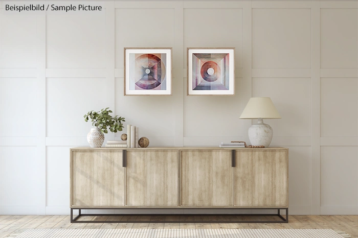 Modern living room with a wooden sideboard, abstract art, decorative plants, table lamp, and white paneled walls.