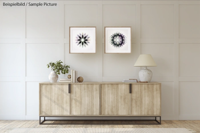 Minimalist living room with wooden sideboard, two framed abstract art pieces, lamp, plant, and decorative items.