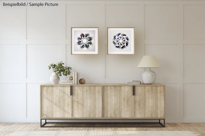 Minimalistic room decor with wooden sideboard, lamp, potted plant, and abstract floral art on white paneled wall.