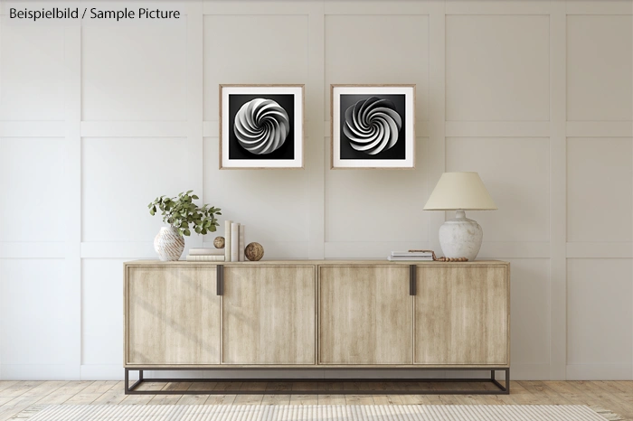 Minimalist living room with wooden console, two abstract black and white art pieces, and decorative objects.