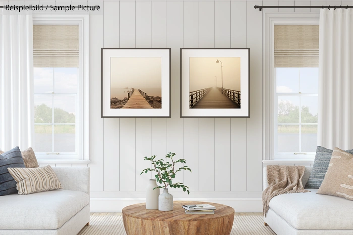 Modern living room with two framed landscape photos, white paneled walls, neutral sofas, and a wooden coffee table.