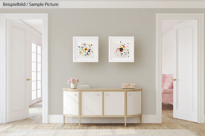 Minimalist hallway with a console table and two abstract paintings on a light gray wall, flanked by doorways.