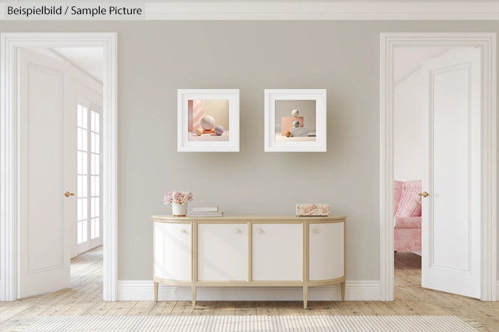 Elegant hallway interior with modern art, light gray walls, a sideboard, and soft lighting from a nearby window.