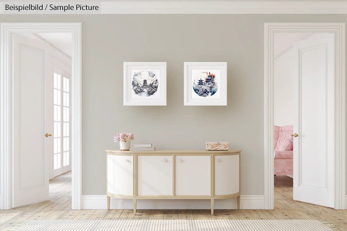 Elegant living room with light gray walls, two framed artworks, and a white sideboard in the center.