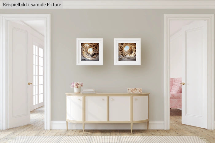 Elegant room interior with a sideboard, decorative items, and two framed art pieces on a light gray wall.