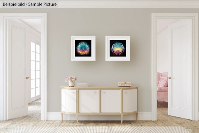 Modern living room with abstract art, white console table, and light decor. Two colorful framed artworks on wall.