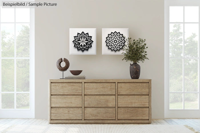 Minimalist room with wooden dresser, black and white floral wall art, and decorative items under large windows.