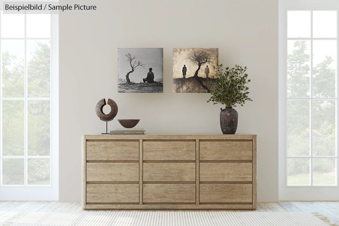 Minimalist room with wooden sideboard, two framed art pieces, sculpture, and potted plant against a light wall.