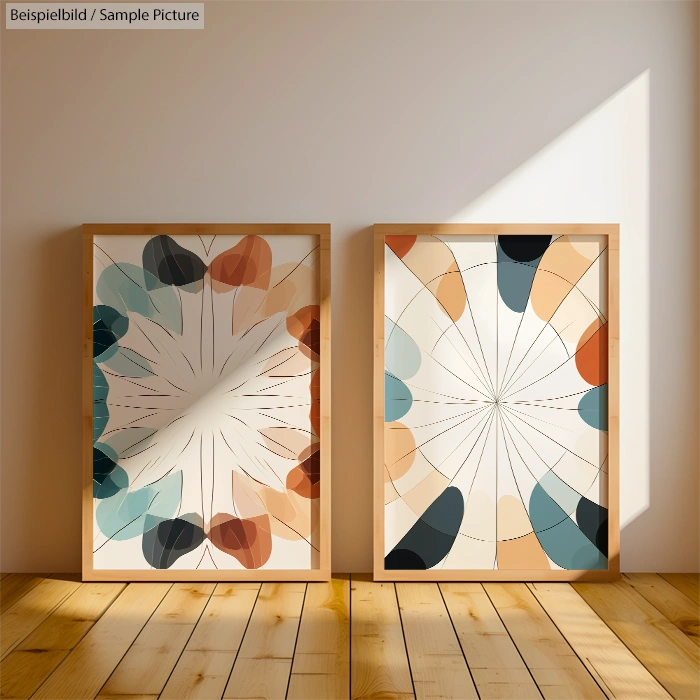 Two framed abstract artworks with geometric shapes in blue, orange, and brown, leaning against a sunlit wooden wall.