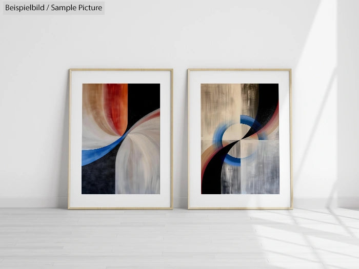 Two abstract framed paintings with curved lines and bold colors, leaning against a white wall in a well-lit room.