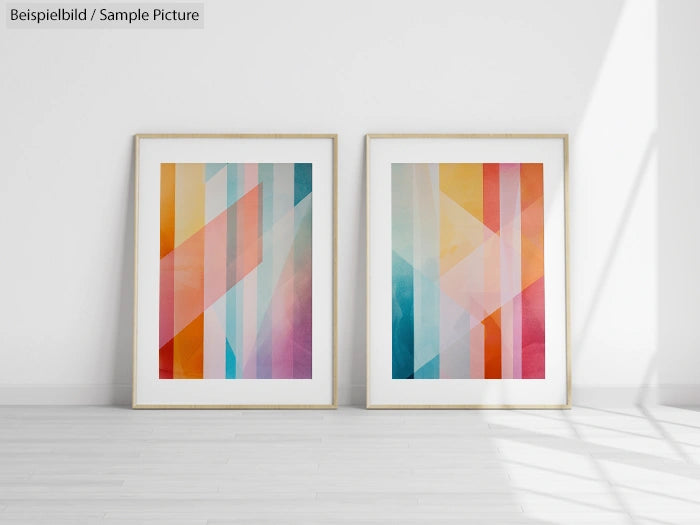 Two framed abstract geometric paintings with colorful stripes and gradients leaning against a white wall.