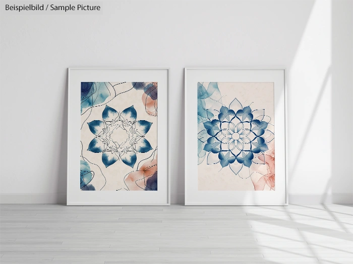 Two framed abstract floral artworks with blue petals on white background, leaning against a white wall in a sunlit room.