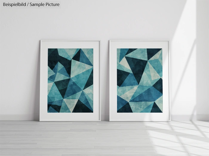 Two framed abstract geometric art pieces with blue and teal triangles, leaning against a white wall in a sunlit room.