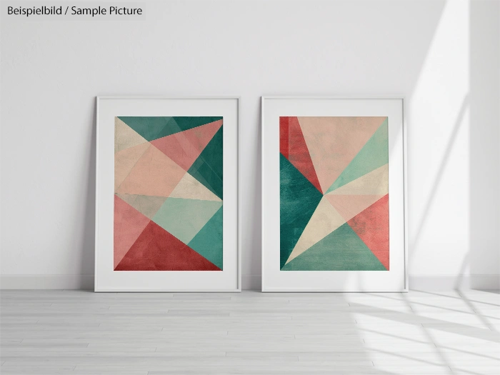 Two framed geometric abstract art pieces with green, pink, and beige triangles, displayed on a light wooden floor.