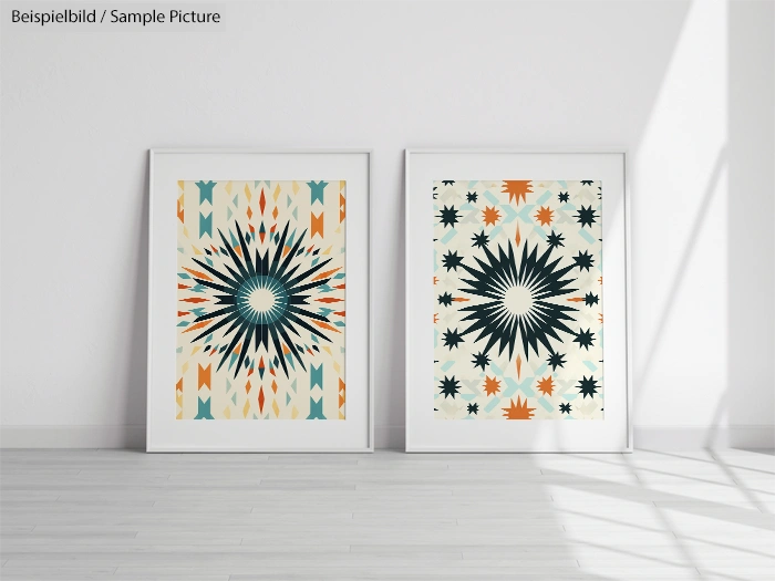 Two framed geometric starburst art prints with orange, teal, and black patterns on a white wall in a minimalist room.