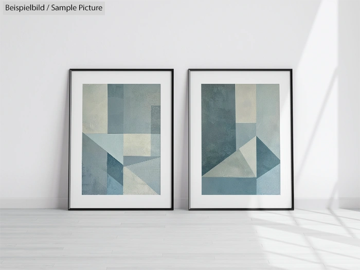 Two framed abstract geometric paintings with shades of blue and gray, on a white wall in a bright room.