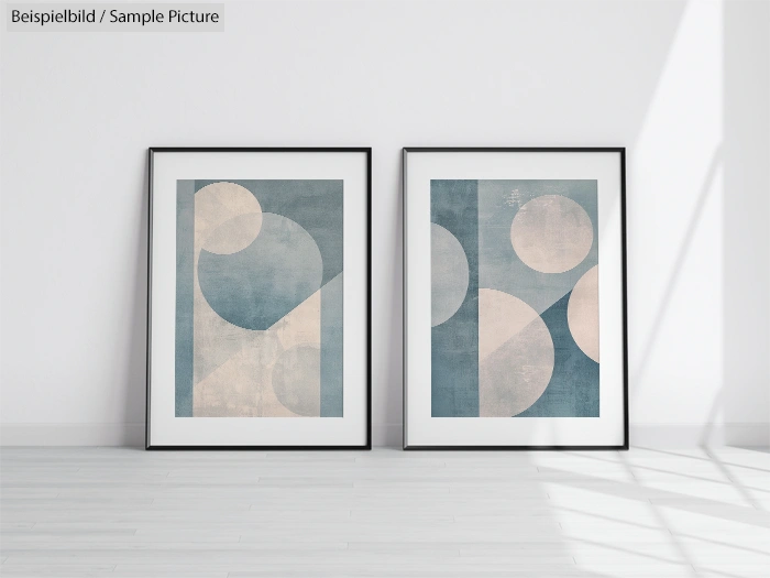 Minimalist art prints with geometric shapes in blue and cream tones, displayed in matching black frames on a white wall.