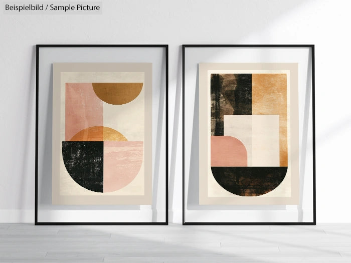 Two framed abstract geometric art pieces with sections in black, pink, and gold, displayed on a light wood floor.