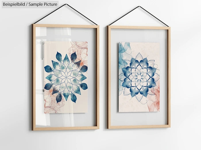 Two framed artworks featuring floral mandala designs in blue and pink tones, hung on a white wall.