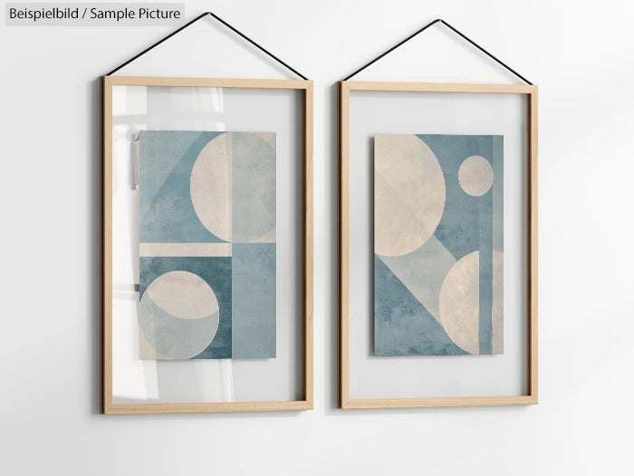 Two framed abstract art prints with geometric shapes in blue and beige, hung on a white wall with black string.