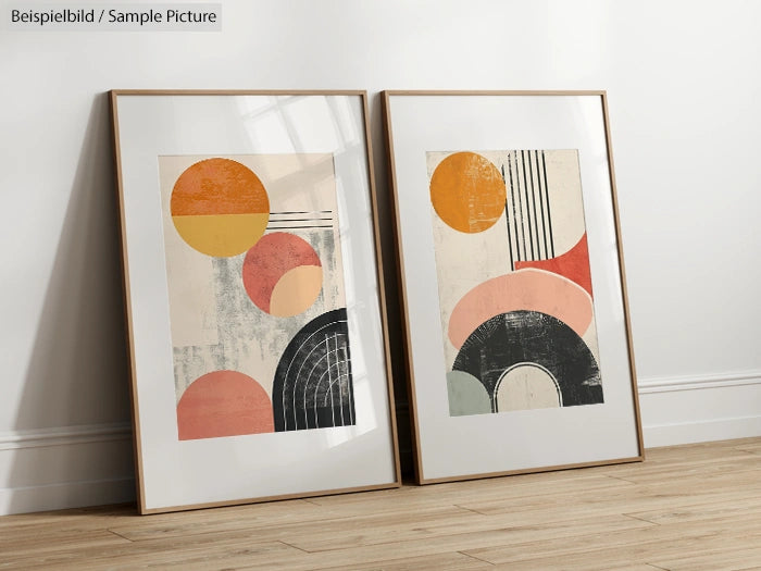 Pair of framed abstract prints with geometric shapes in warm colors, leaning against a white wall.