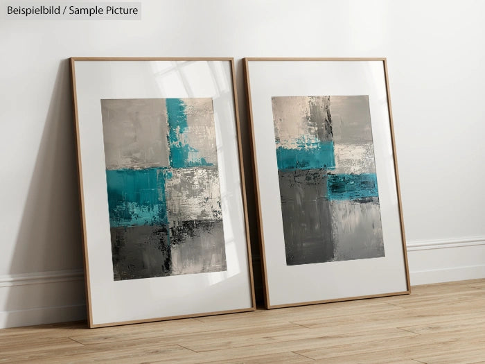 Two abstract paintings with teal and gray geometric blocks in wooden frames on a wooden floor.