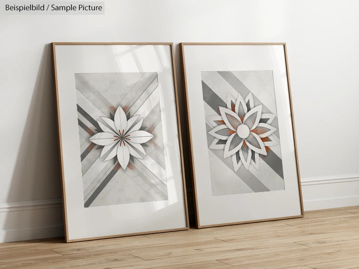 Two framed geometric floral art prints leaning against a white wall on a wooden floor.