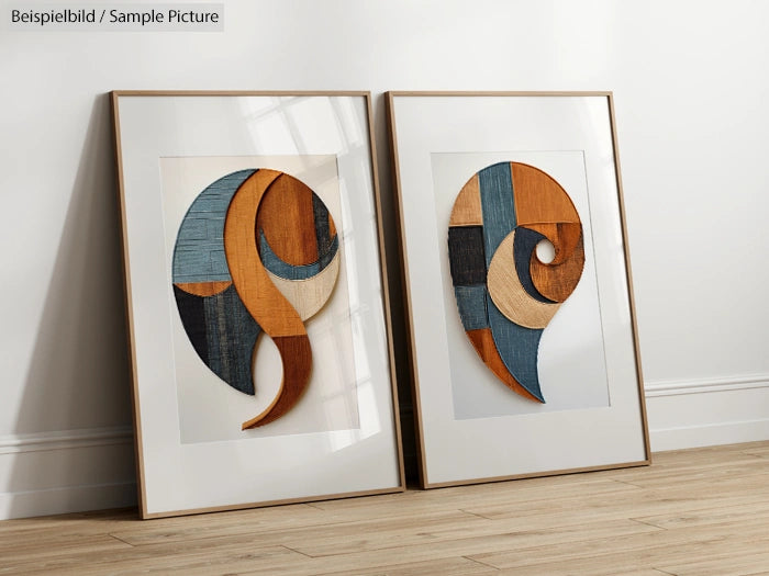 Two framed modern abstract artworks with geometric designs in earth tones, leaning against a white wall on wooden floor.