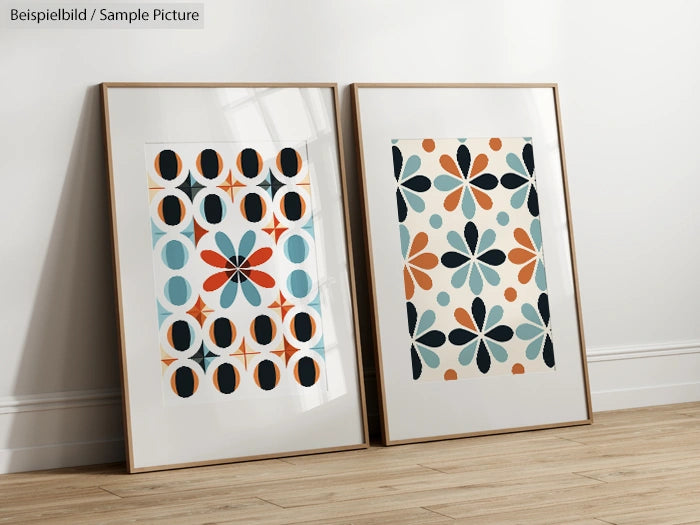 Two framed geometric posters with colorful patterns, leaning against a white wall, on a wooden floor.