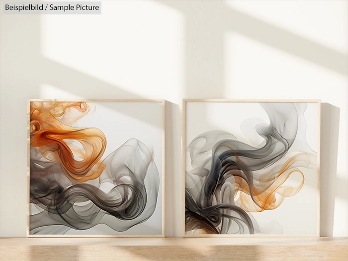 Pair of abstract paintings with swirling gray and orange patterns, set against a sunlit wall.