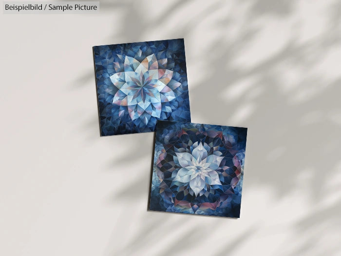 Two square fractal art pieces with blue and pink mandala designs on a light surface with subtle shadows.