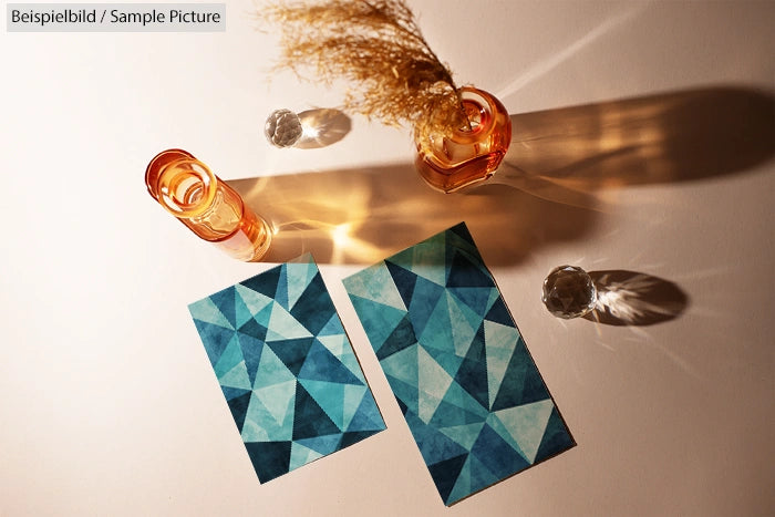 Geometric blue pattern art displayed on a table with amber glass vases casting shadows.