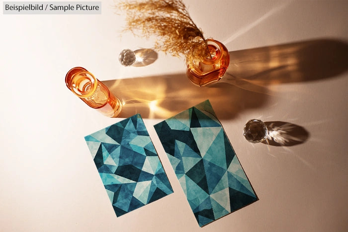 Geometric blue abstract artwork beside amber vases casting shadows on a light surface.