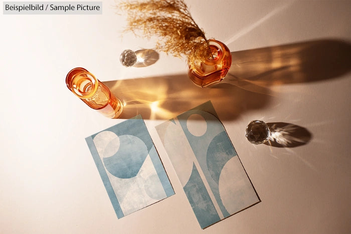 Artistic arrangement of dried flowers in amber glass vases on a table with geometric blue and white abstract prints.