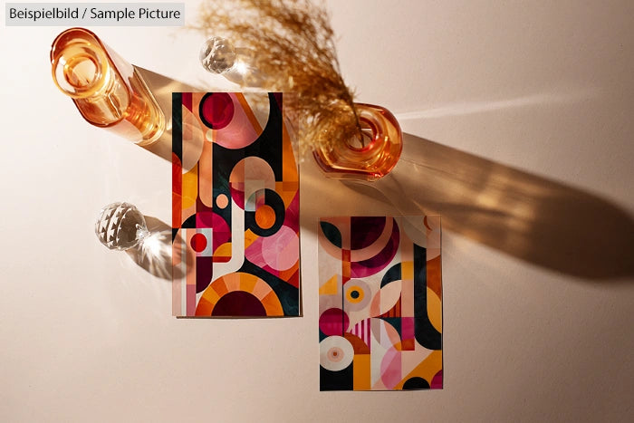 Abstract art postcards with geometric patterns in warm tones, placed on a lit surface with vases and dried flowers.